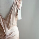 Dlhé ružové spoločenské šaty s luxusným leskom očaria výraznými volánmi na ramenách a zavinovacím výstrihom, ktorý elegantne tvaruje dekolt. Hladká sukňa s rozparkom dodáva modelu ženskosť a voľnosť pohybu. Perfektná voľba na svadby, oslavy či večerné príležitosti.