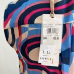 Farebné letné šaty s originálnym geometrickým vzorom okamžite pritiahnu pozornosť a dodajú sviežosť každému outfitu. Prekladaný výstrih a opasok v páse krásne formujú postavu a zvýrazňujú ženské krivky. Ľahký a vzdušný materiál zabezpečuje pohodlie počas horúcich letných dní.