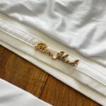 Štýlové biele dvojdielne plavky s asymetrickým ramienkom a ozdobnou 3D kvetinou sú dokonalou kombináciou trendu a jemnej elegancie pre mladé slečny. Vrchný diel zdobí decentný zlatý nápis značky, ktorý dodáva kúsku exkluzívny nádych. Pohodlný strih s vyšším spodným dielom zabezpečí komfort pri plávaní aj opaľovaní.